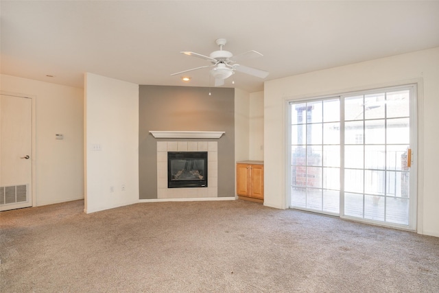 unfurnished living room with ceiling fan, light colored carpet, and a fireplace