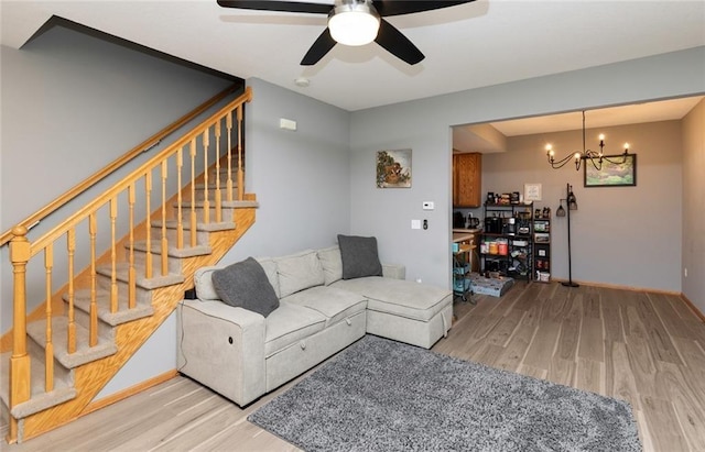 living room featuring light wood-type flooring and ceiling fan with notable chandelier