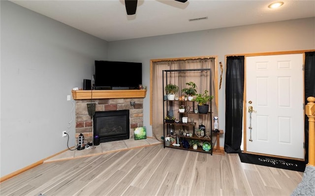 living room featuring hardwood / wood-style flooring, ceiling fan, and a fireplace