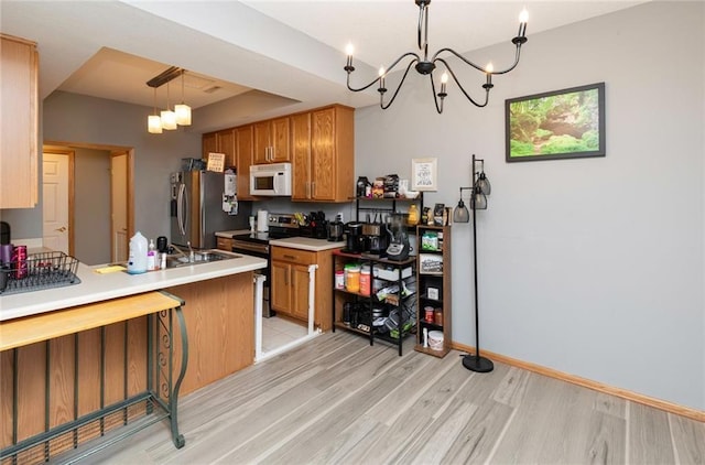 kitchen featuring light hardwood / wood-style floors, pendant lighting, stainless steel appliances, and a chandelier