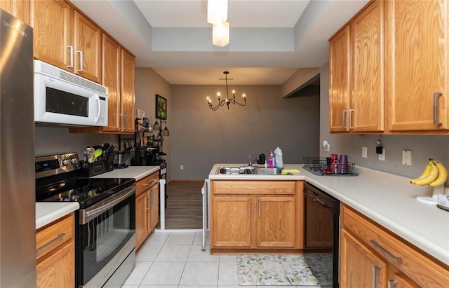 kitchen with appliances with stainless steel finishes, sink, hanging light fixtures, kitchen peninsula, and a chandelier