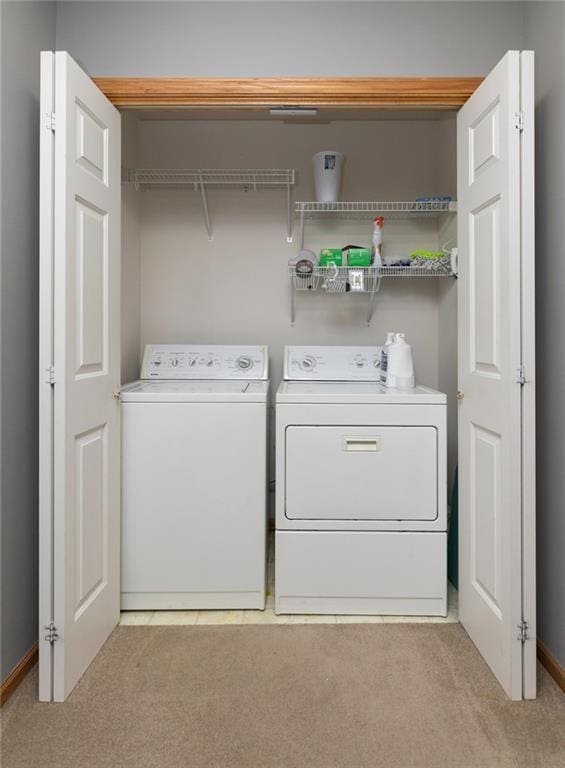 laundry room featuring washer and clothes dryer and light colored carpet