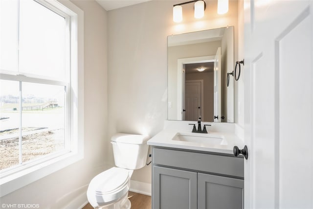 bathroom with wood finished floors, baseboards, vanity, and toilet