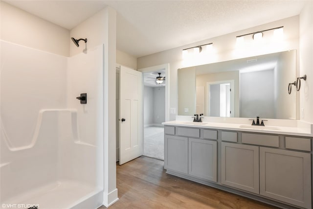 full bath with walk in shower, wood finished floors, a sink, and double vanity