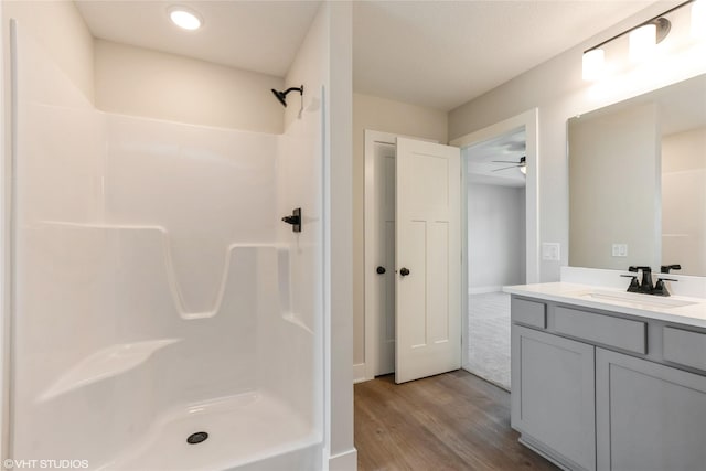 full bathroom with a shower stall, a ceiling fan, vanity, and wood finished floors