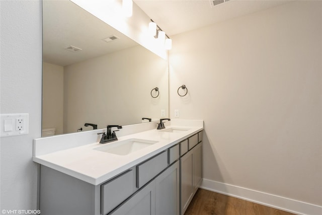 bathroom featuring wood finished floors, visible vents, baseboards, and a sink