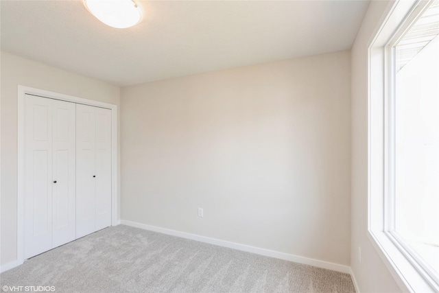 unfurnished bedroom with carpet floors, baseboards, and multiple windows