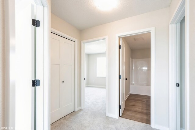 hallway featuring baseboards and light colored carpet