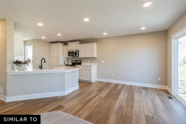 kitchen featuring appliances with stainless steel finishes, light hardwood / wood-style flooring, white cabinets, and sink