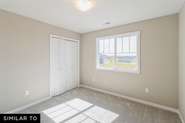 unfurnished bedroom with light carpet and a closet