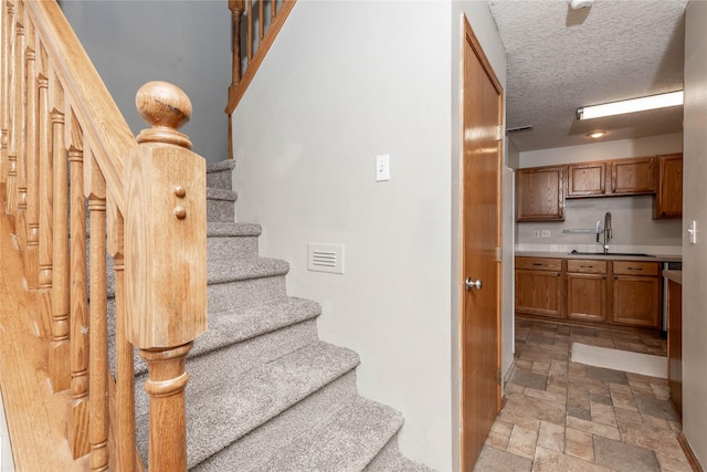 stairs with sink and a textured ceiling