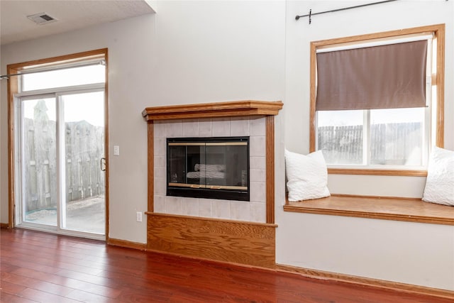 unfurnished living room featuring a tiled fireplace and hardwood / wood-style floors