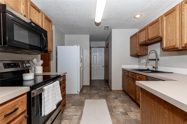 kitchen featuring stainless steel electric range oven, sink, a textured ceiling, and white fridge with ice dispenser