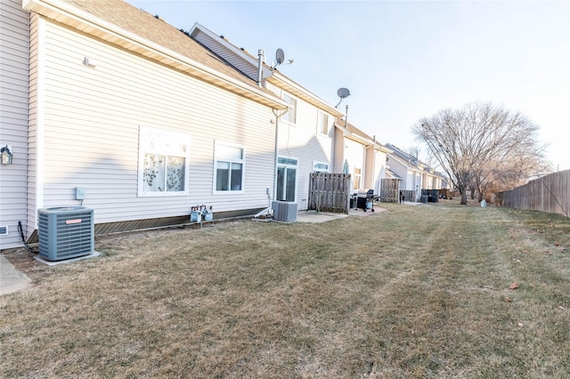 rear view of house with cooling unit and a yard