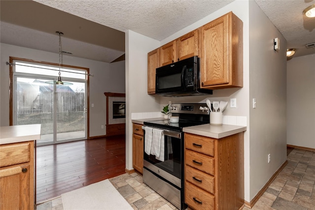 kitchen featuring a textured ceiling, stainless steel electric stove, a tiled fireplace, and pendant lighting