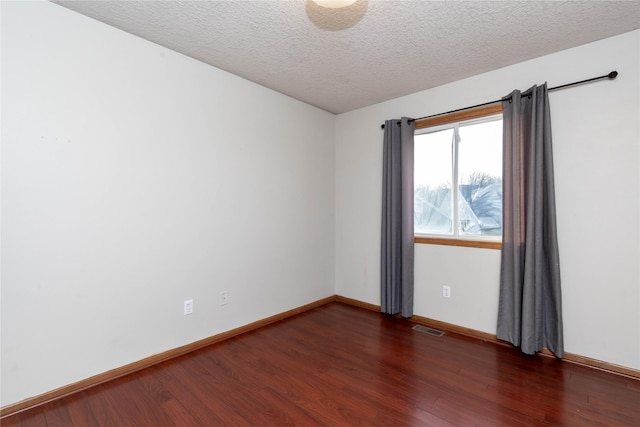 empty room featuring a textured ceiling and dark hardwood / wood-style flooring