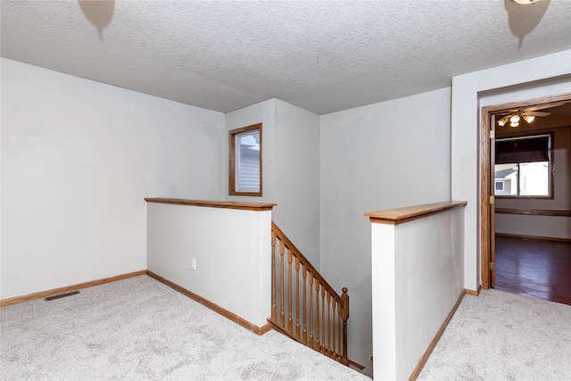 hall with light carpet and a textured ceiling