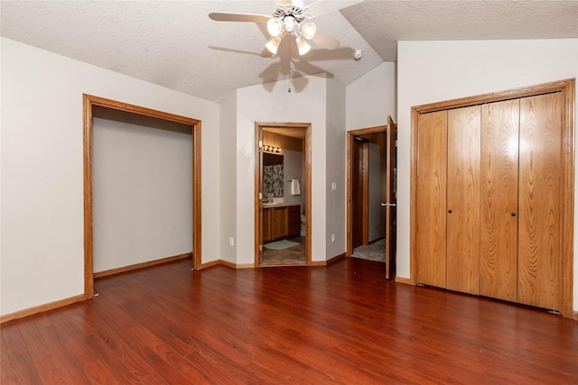 unfurnished bedroom with lofted ceiling, ceiling fan, a textured ceiling, a closet, and dark hardwood / wood-style flooring