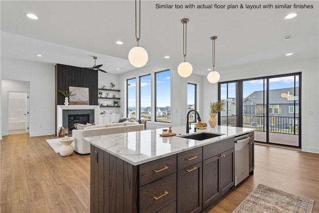 kitchen with a center island with sink, pendant lighting, stainless steel dishwasher, light stone counters, and sink