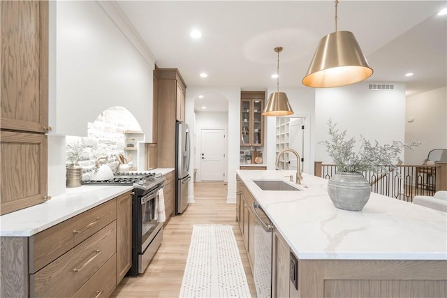 kitchen featuring stainless steel appliances, a large island, hanging light fixtures, and sink