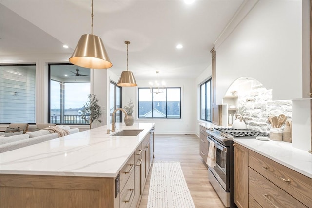 kitchen with decorative light fixtures, sink, light stone countertops, stainless steel appliances, and a large island