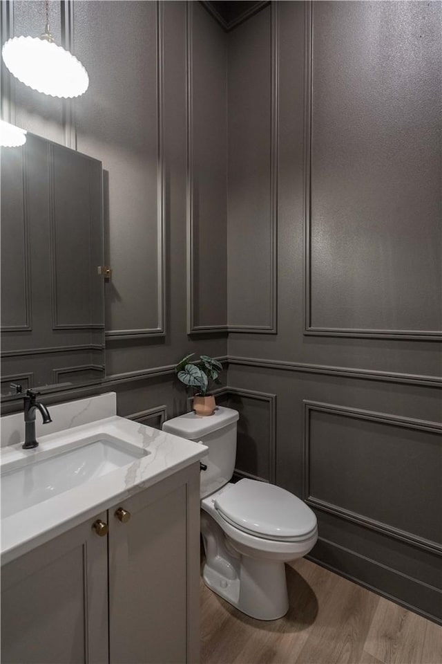 bathroom with hardwood / wood-style floors, toilet, and vanity