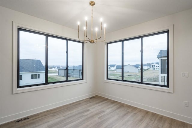 spare room with wood-type flooring and a notable chandelier