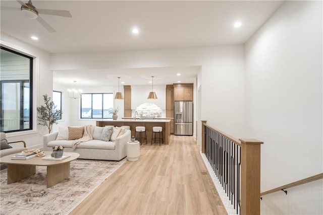 living room with light wood-type flooring, ceiling fan, and sink