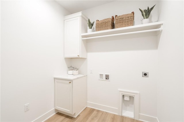 washroom with light wood-type flooring, hookup for an electric dryer, hookup for a washing machine, and cabinets