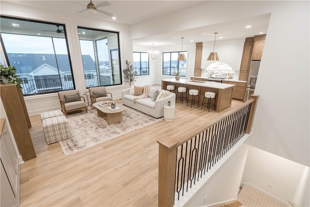 living room with ceiling fan, sink, and light hardwood / wood-style flooring