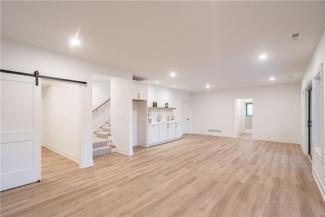 basement with a barn door and light hardwood / wood-style flooring