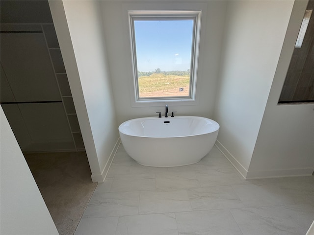 3034 NW Beechwood Dr, Grimes, IA 50111 - bathroom featuring marble look tiles and a freestanding bath
