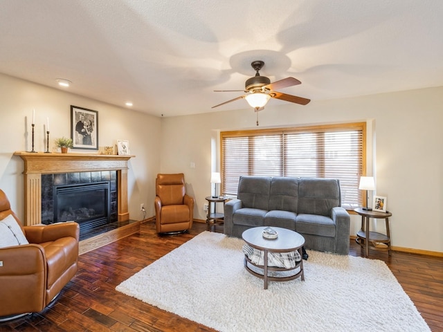 living room featuring ceiling fan, dark wood-type flooring, and a tile fireplace