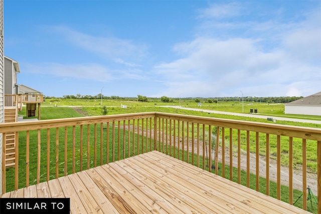 wooden terrace featuring a rural view and a yard