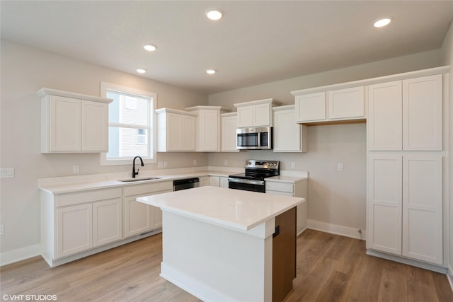 kitchen featuring white cabinets, light wood-style floors, appliances with stainless steel finishes, and a sink