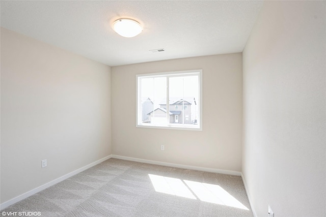 spare room with light colored carpet, baseboards, and visible vents