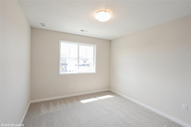 carpeted empty room featuring visible vents and baseboards