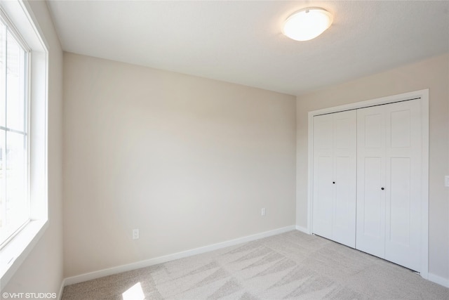 unfurnished bedroom with carpet, a closet, and baseboards