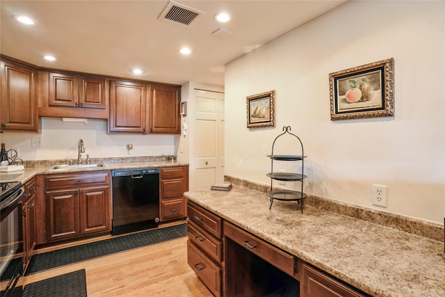 kitchen with sink, black appliances, light wood-type flooring, and light stone countertops