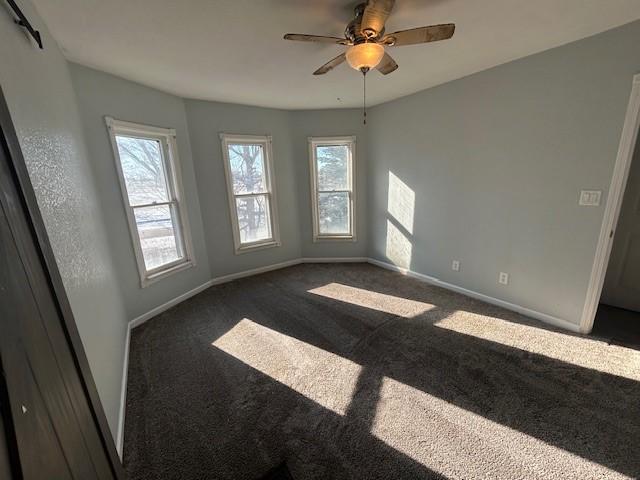 carpeted spare room featuring ceiling fan, a healthy amount of sunlight, and a barn door