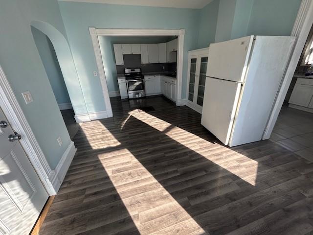 kitchen with white cabinetry, dark wood-type flooring, stainless steel stove, and white refrigerator