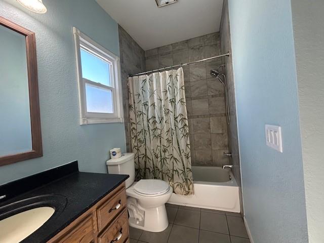 full bathroom with shower / bath combo with shower curtain, tile patterned floors, vanity, and toilet