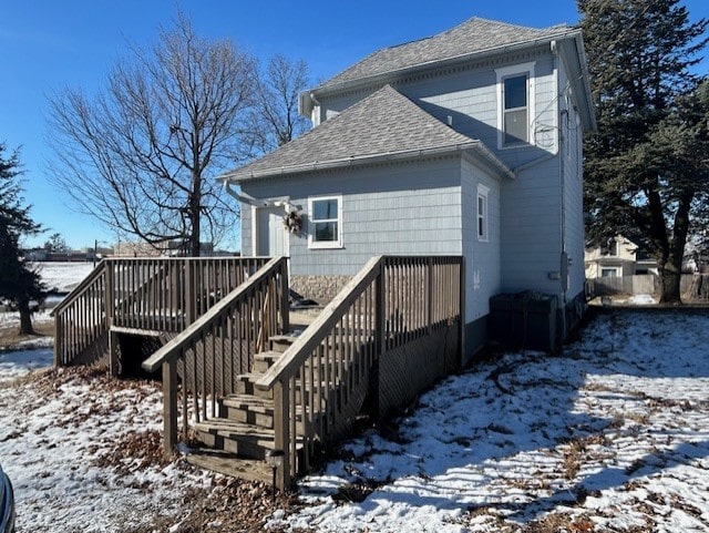 snow covered back of property featuring a deck