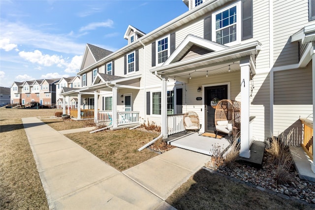 multi unit property featuring covered porch and a front lawn