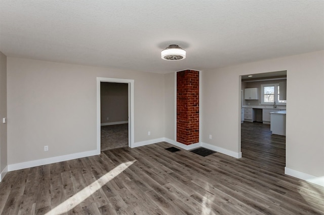 unfurnished living room with dark wood-type flooring and a textured ceiling