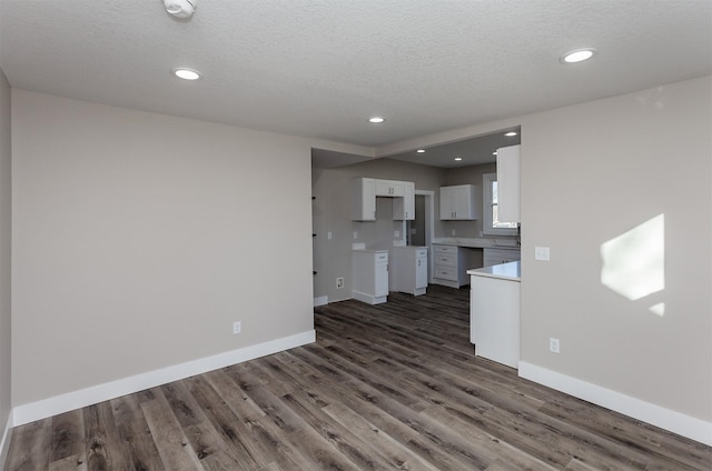 unfurnished living room with dark wood-type flooring and a textured ceiling