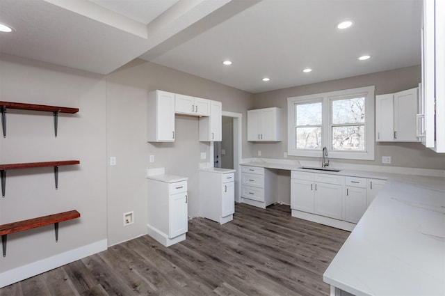 kitchen with dark wood-type flooring, sink, white cabinetry, and light stone countertops