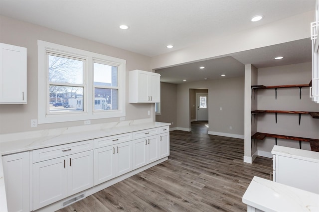 kitchen featuring light stone countertops, white cabinets, and dark hardwood / wood-style flooring