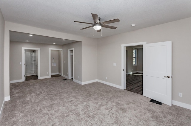 carpeted spare room featuring ceiling fan and a textured ceiling