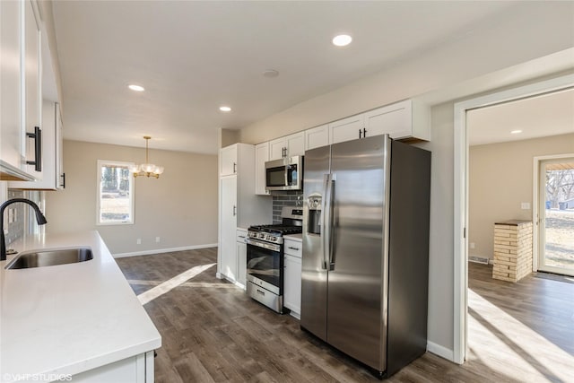 kitchen featuring dark hardwood / wood-style floors, pendant lighting, white cabinetry, sink, and stainless steel appliances